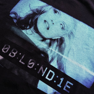 Close-up of a graphic t-shirt with a stylized face design and text on a dark background.